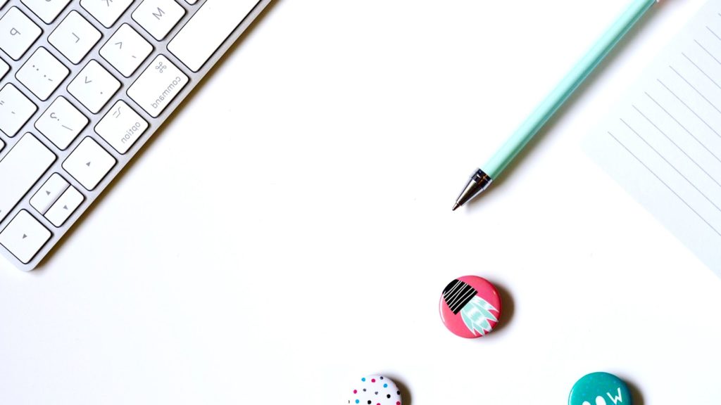 Flatlay photo of a keyboard and some colorful pins.