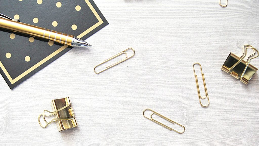 Flatlay photo of some gold paperclips and a black napkin