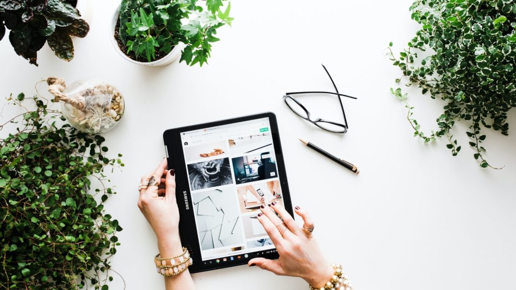 Flatlay photo of an iPad and some plants. A Woman appears to be working on her online business.